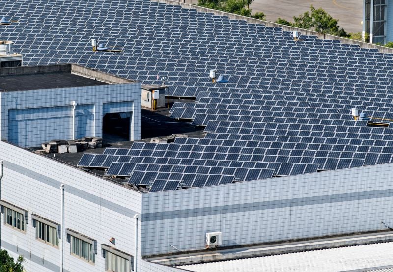 A large industrial building covered with rooftop solar panels used for generating electricity.