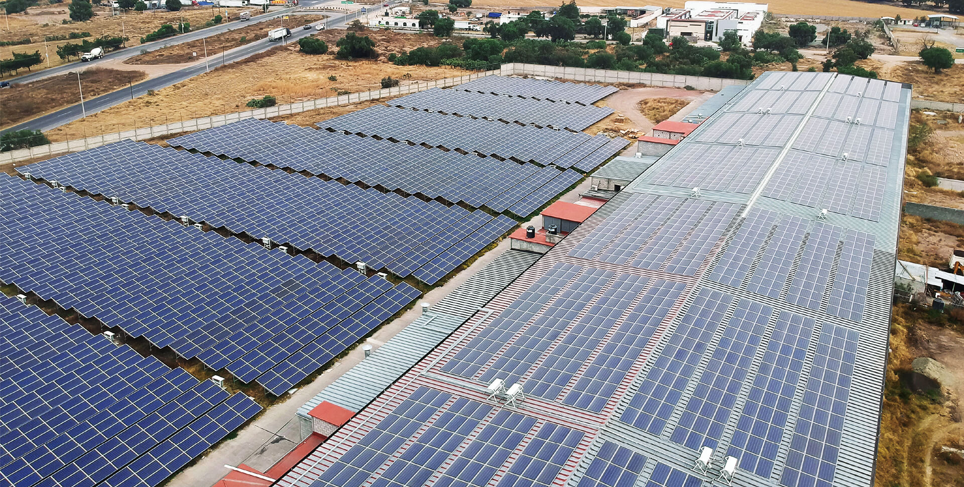 A large solar installation showing both rooftop and ground-mounted solar panels used for renewable power generation.