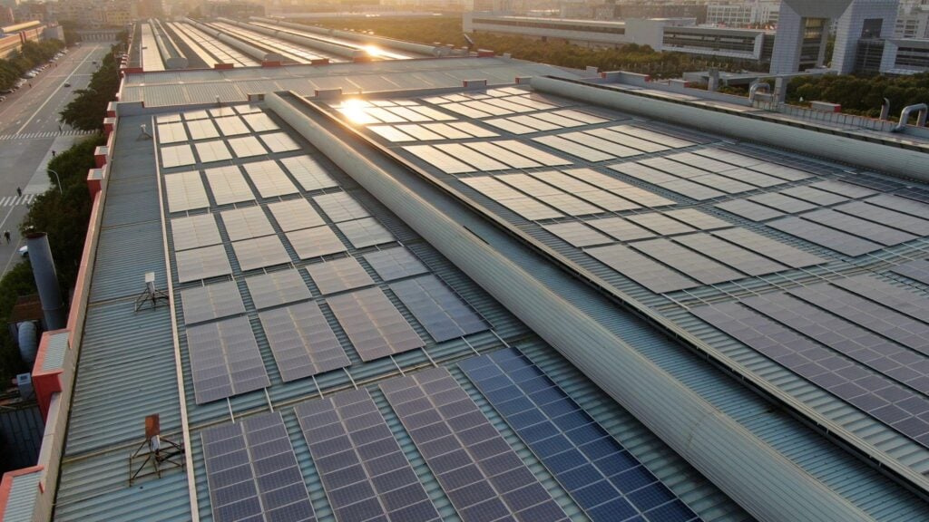 Business professionals discussing RESCO solar model concerns with solar panels in background highlighting contract security and system reliability